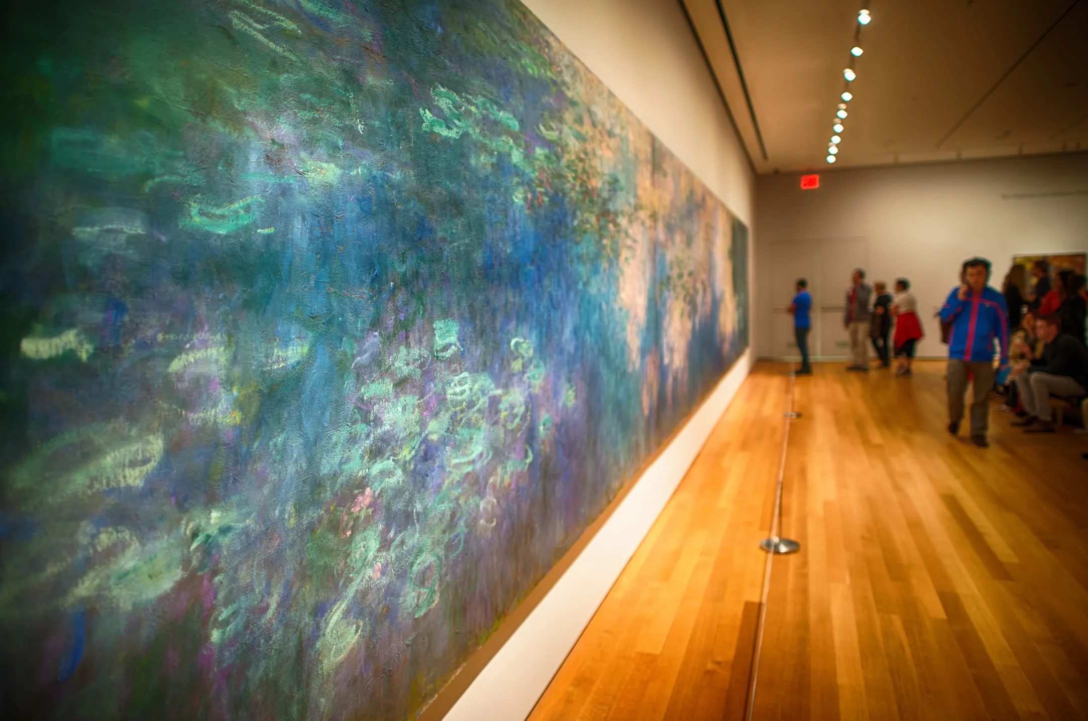 Sala de una galería de arte con visitantes recorriendo la exposición