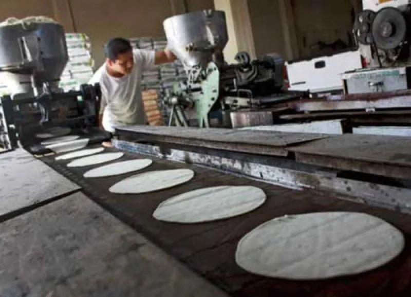 Operario trabajando en una máquina tortilladora industrial mexicana